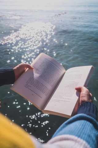 Serene moment of reading by the ocean in Cape Town with shimmering waters.