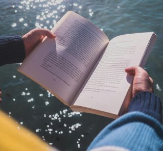 Serene moment of reading by the ocean in Cape Town with shimmering waters.