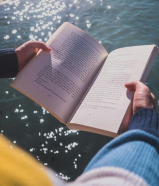Serene moment of reading by the ocean in Cape Town with shimmering waters.