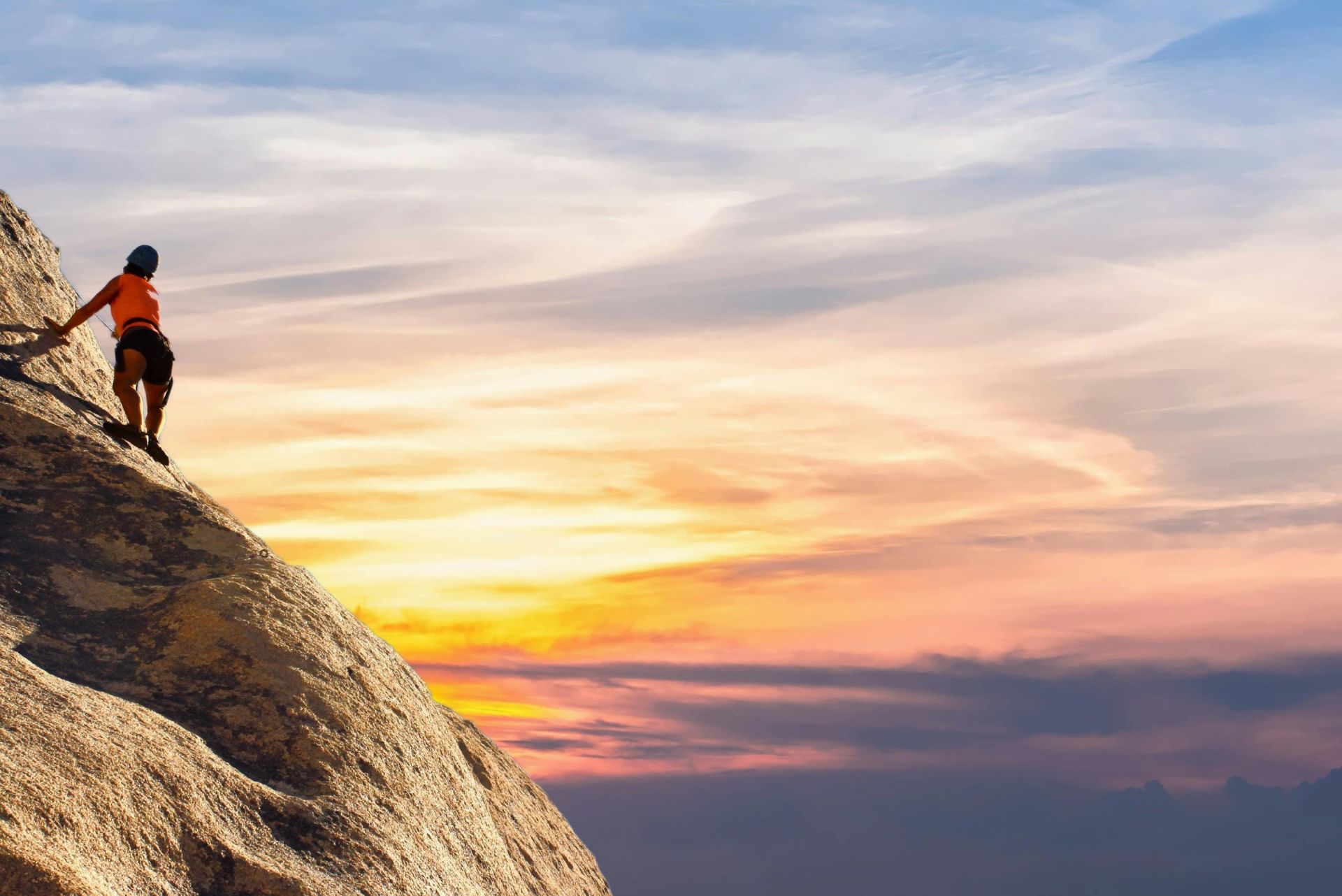 Climber conquers rock face at sunset, embracing the thrill and challenge.